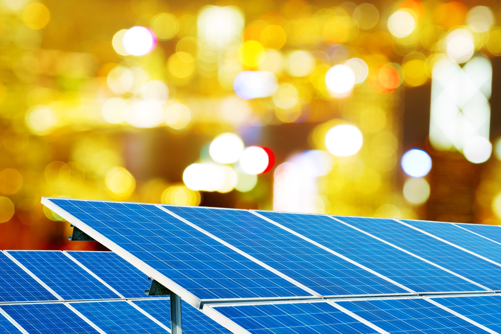 Pannelli fotovoltaici in primo piano con sfondo di luci sfocate della città. Incentivi fotovoltaico per le imprese
