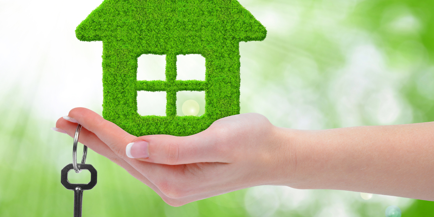 Casa verde appoggiata su una mano con una chiave. Case green: stop vendita abitazioni energivore